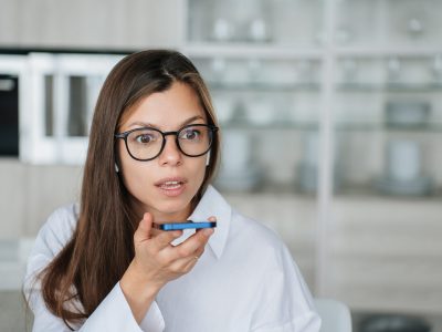 Close up of brunette hispanic woman with wide opened eyes recording audio message to partner, shocked by news. Failure, troubles. Scared businesswoman talks with friend. Mockup, problems.